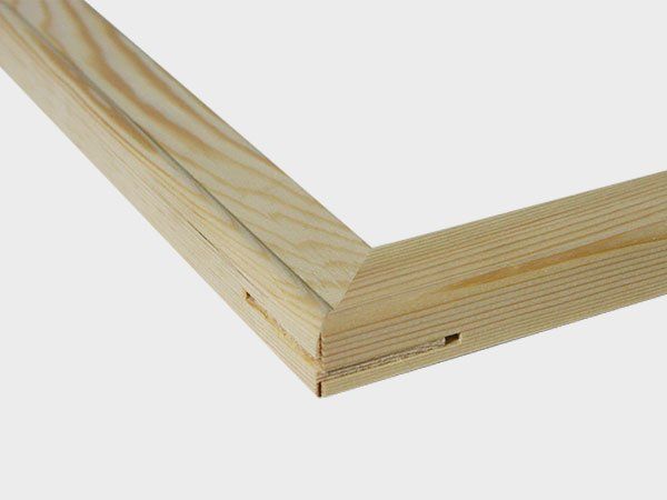 Close-up of a mitered wooden frame corner with light pine grain and a visible joint hole