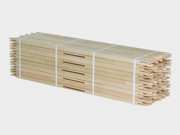 Stacked light wooden slats bundled with white straps on a plain background