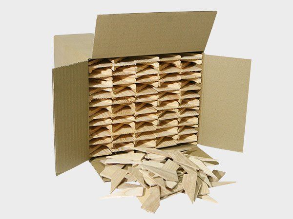 Open cardboard box filled with stacked packing peanuts and shredded paper spilling out