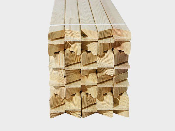 Stacked wooden trim pieces with grooved ends, arranged in a bundle on a white background