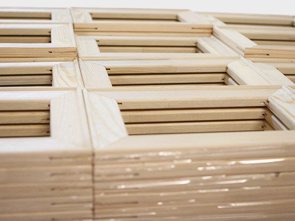 Stacked light wood crates or slatted frames wrapped in clear plastic.