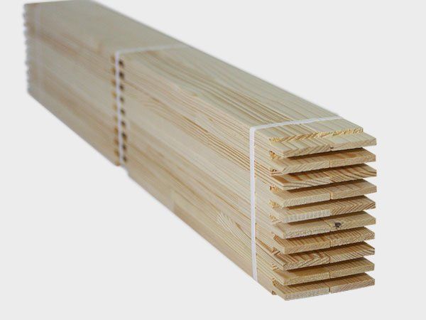 Stack of light wood boards with interlocking grooves, bundled together on a white background