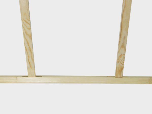 Two light wooden legs attached to a pale horizontal board against a white background