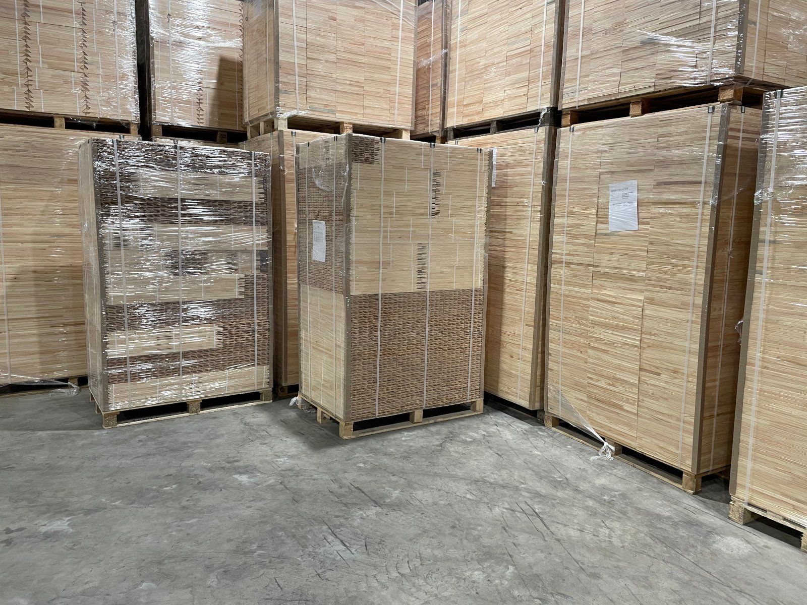 Pallets of stacked cardboard boxes wrapped in plastic in a warehouse aisle