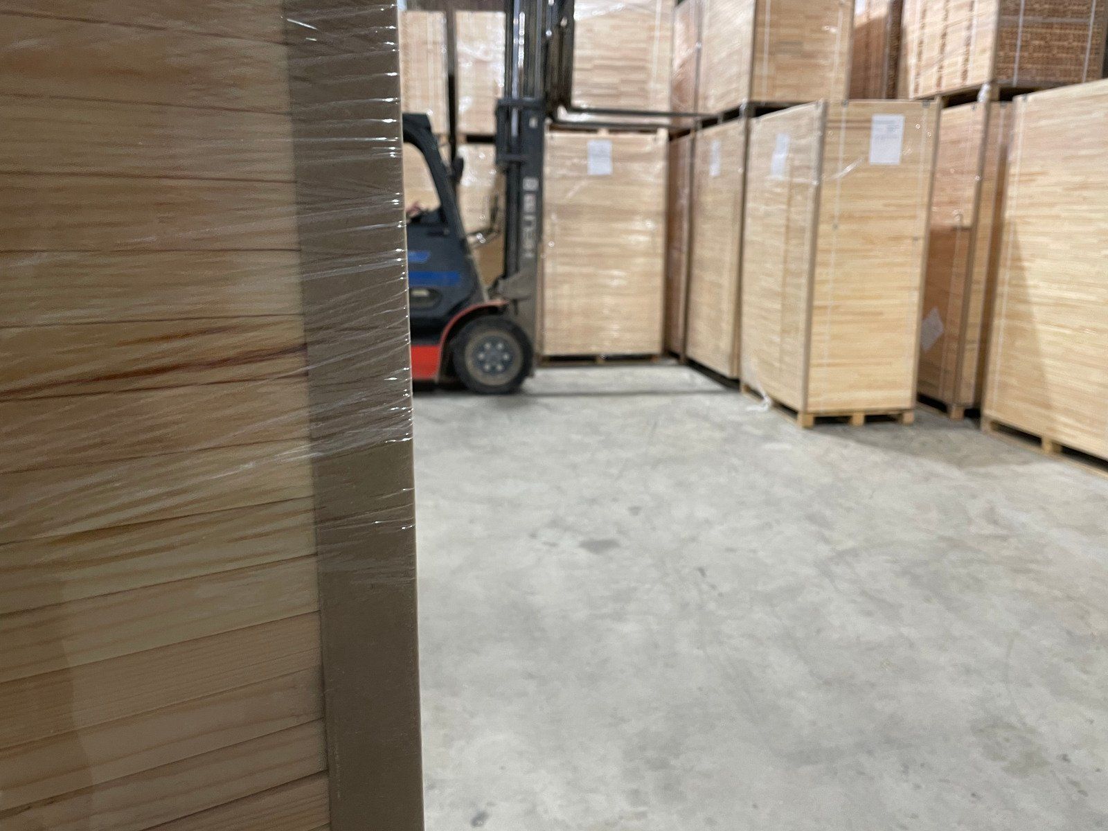 Warehouse aisle with stacked cardboard boxes and a forklift on a concrete floor