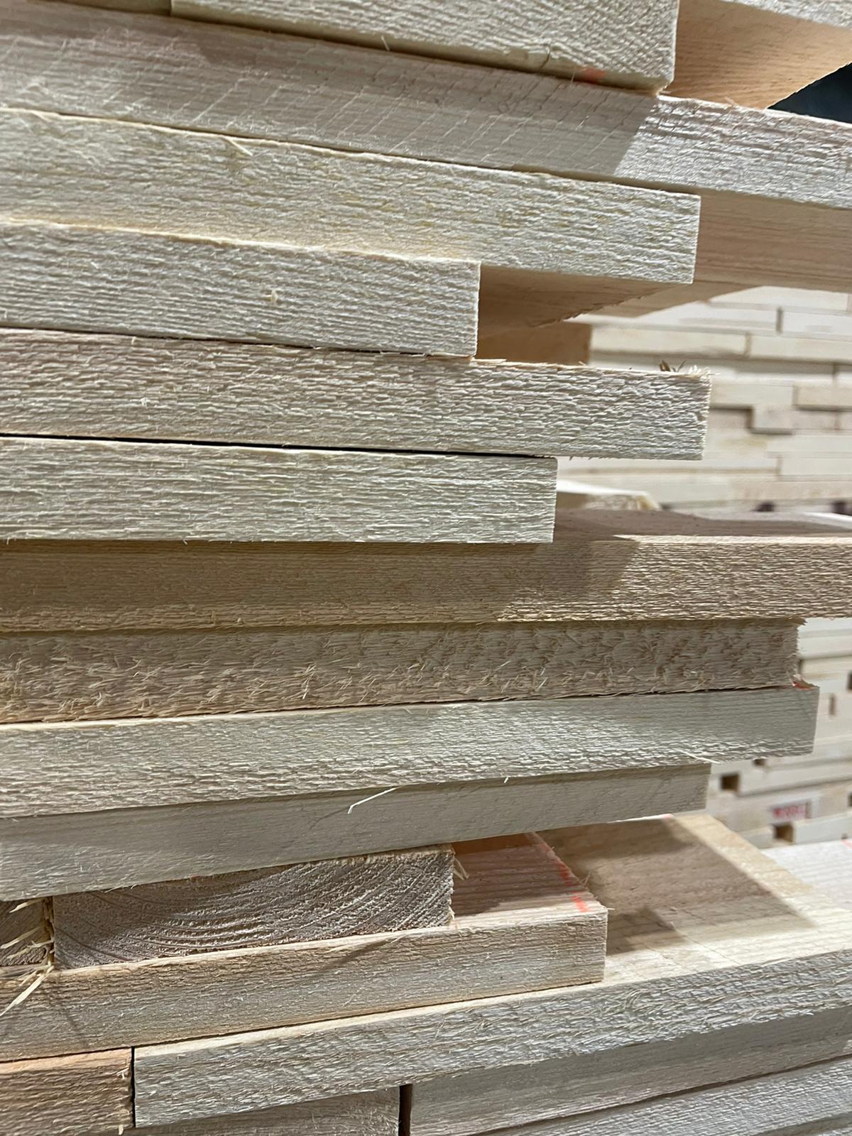 Stacked wooden slats in beige and gray tones, viewed in close-up.