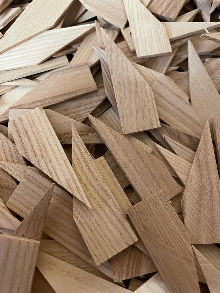 Close-up of assorted light wood wedges and offcuts with visible grain and ridged surfaces