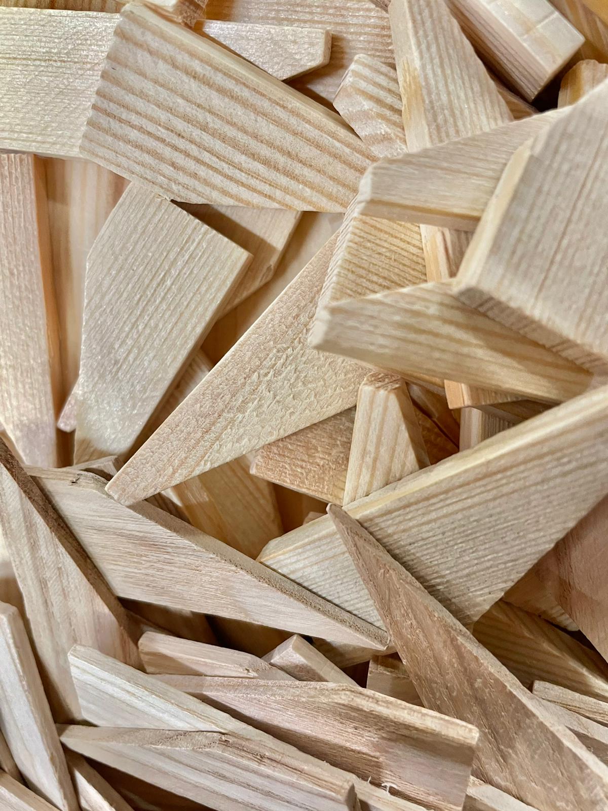 Pile of light-colored wooden wedges and slats, stacked and overlapping in a close-up view