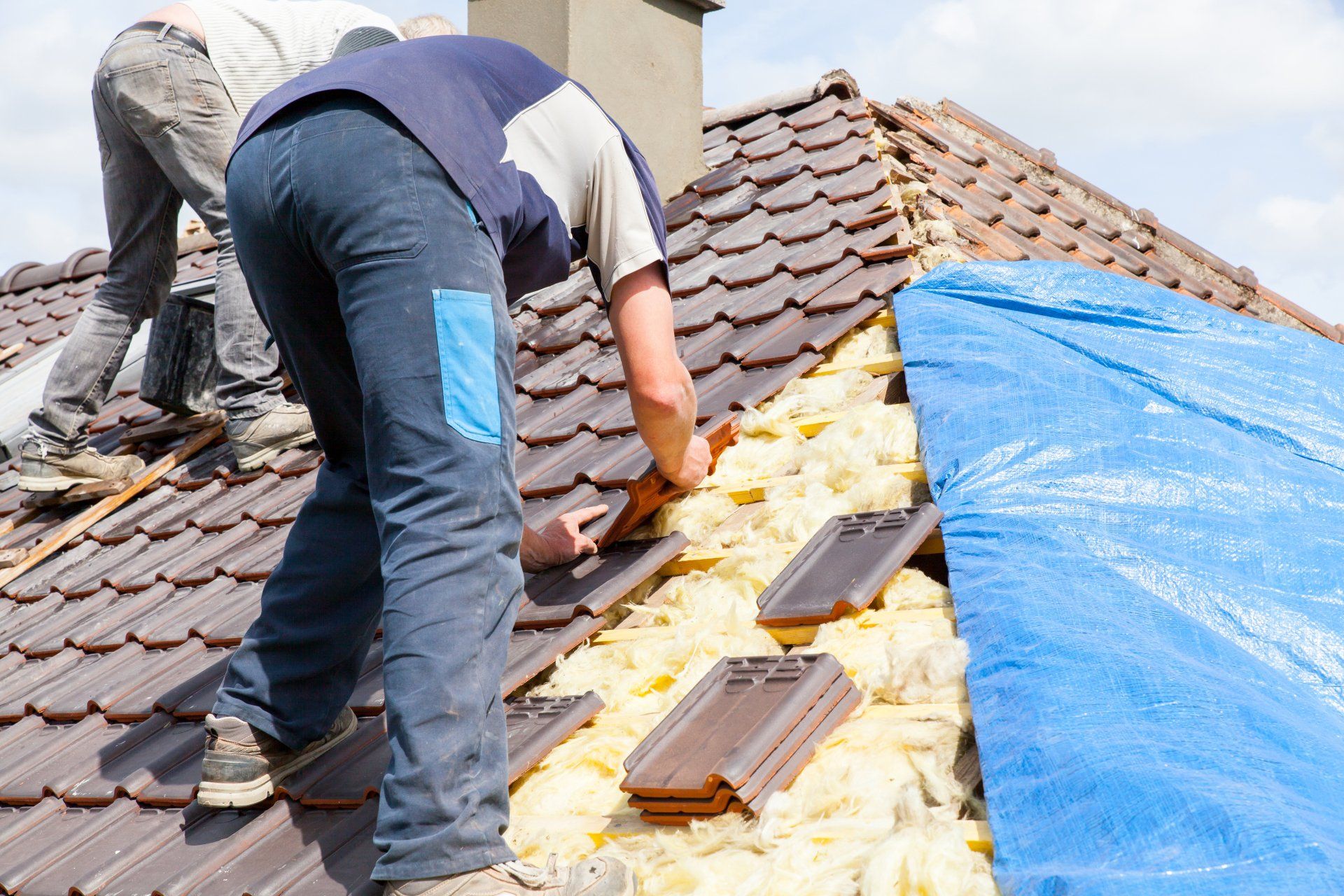 Deux hommes travaillent sur le toit d'une maison.
