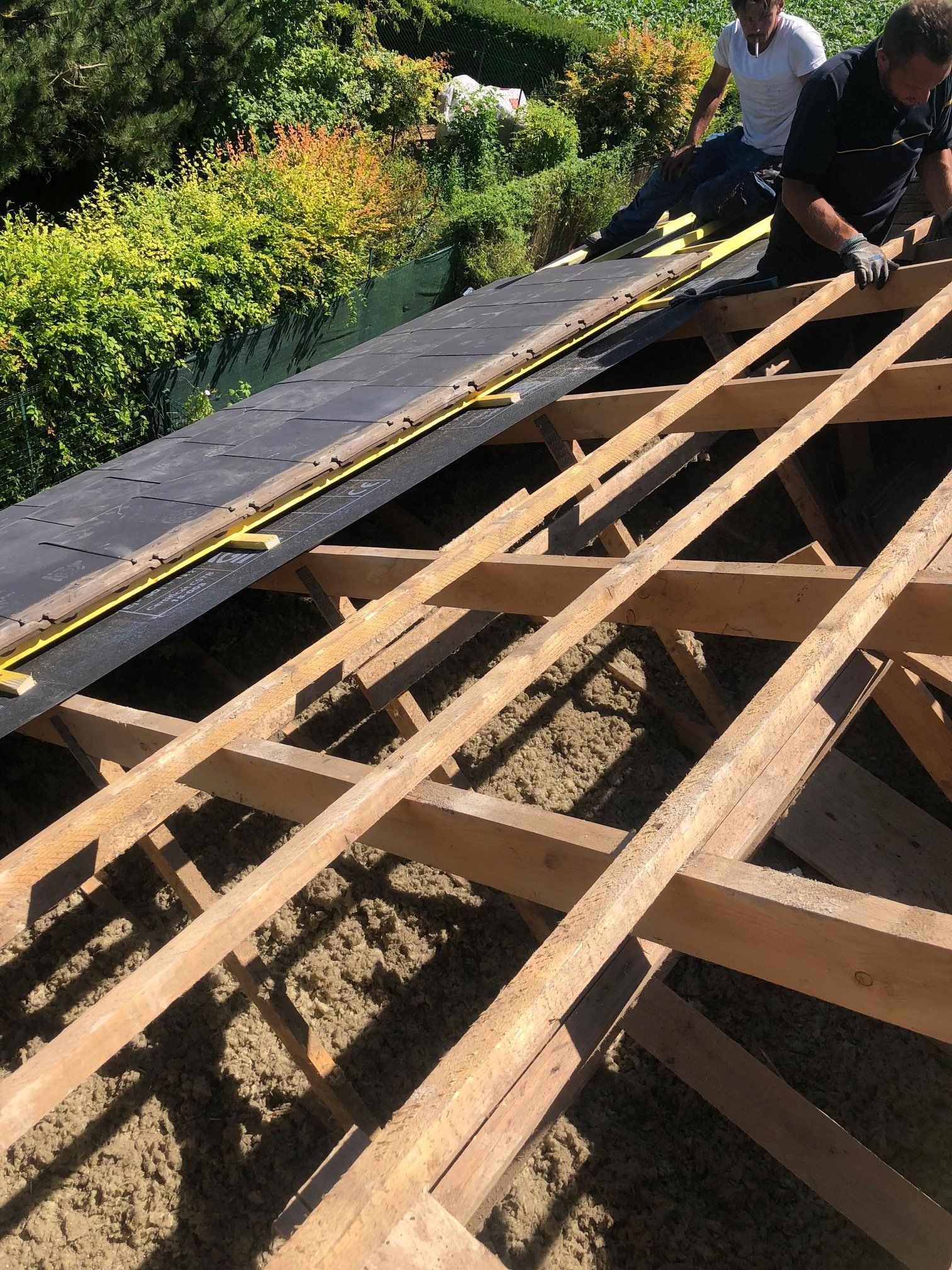 Un homme mesure une structure en bois avec un ruban à mesurer.