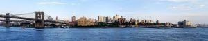 New York City skyline with the Brooklyn Bridge over water.