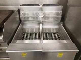 Two commercial deep fryers made of stainless steel side-by-side.