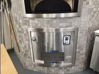Brick oven with stainless steel door and tiled exterior.