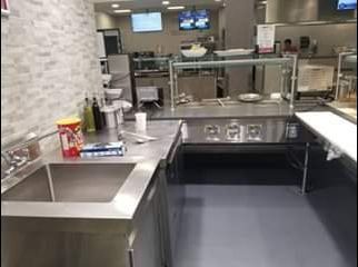 Stainless steel commercial kitchen with a sink, prep area, and food warmers.