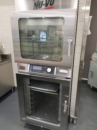 Stainless steel commercial oven with open lower door, digital control panel.