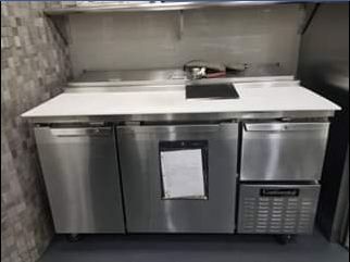 Stainless steel commercial refrigerator with work surface, built-in drawer, and doors.
