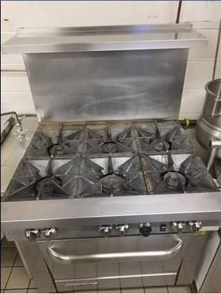 Stainless steel commercial gas range with six burners and oven.