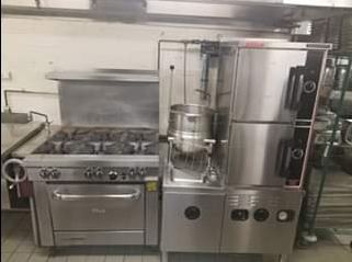Commercial kitchen with stove, large pot, and dishwasher. Stainless steel appliances in a restaurant.
