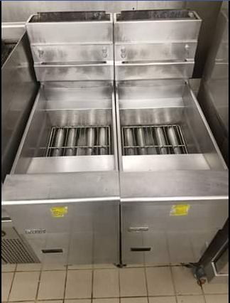 Two stainless steel commercial fryers in a kitchen.