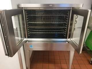Commercial stainless steel oven with glass doors open, revealing multiple racks.