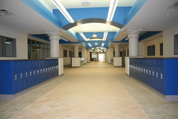 School hallway with blue lockers, columns, and blue and white ceiling.