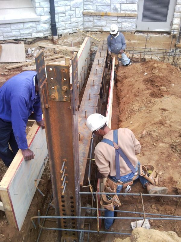 Construction workers building a concrete foundation with steel beams and rebar.