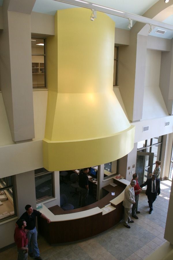 Interior view of a building with a yellow architectural feature above a reception desk, people are standing nearby.