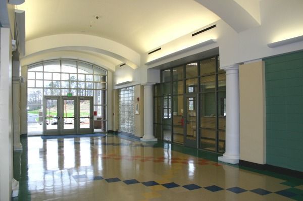 Hallway with arched ceiling, glass doors and windows. The floor is tiled, with white columns.