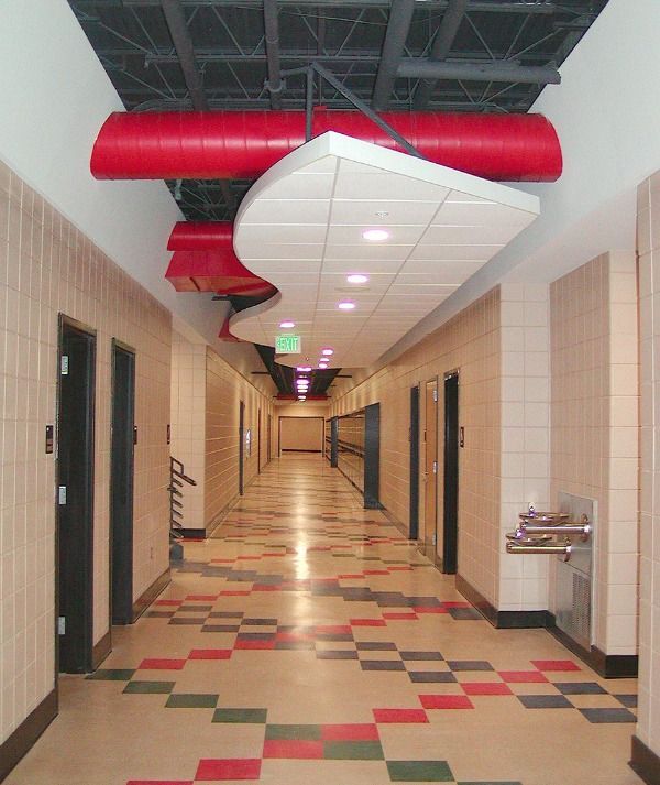 Hallway with patterned floor, beige walls, and red ceiling accents; water fountain on right.