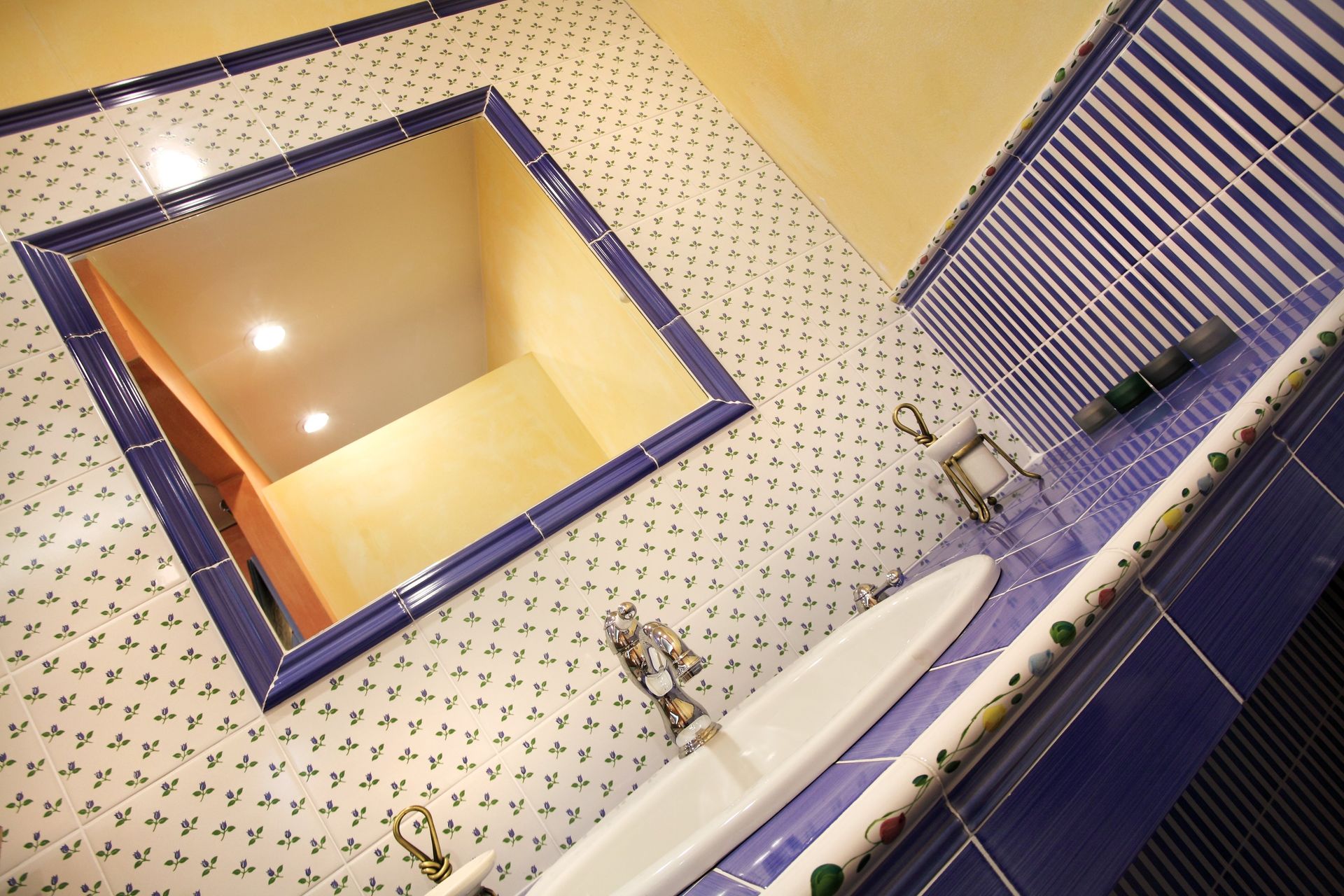 Foto laterale di un bagno con pareti gialle e blu scuro.