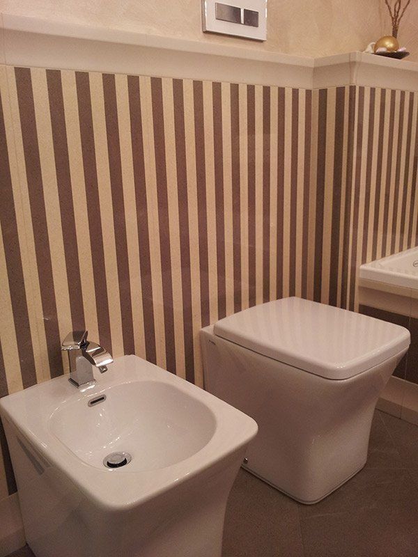 Bidet e bagno con parete a strisce verticali.