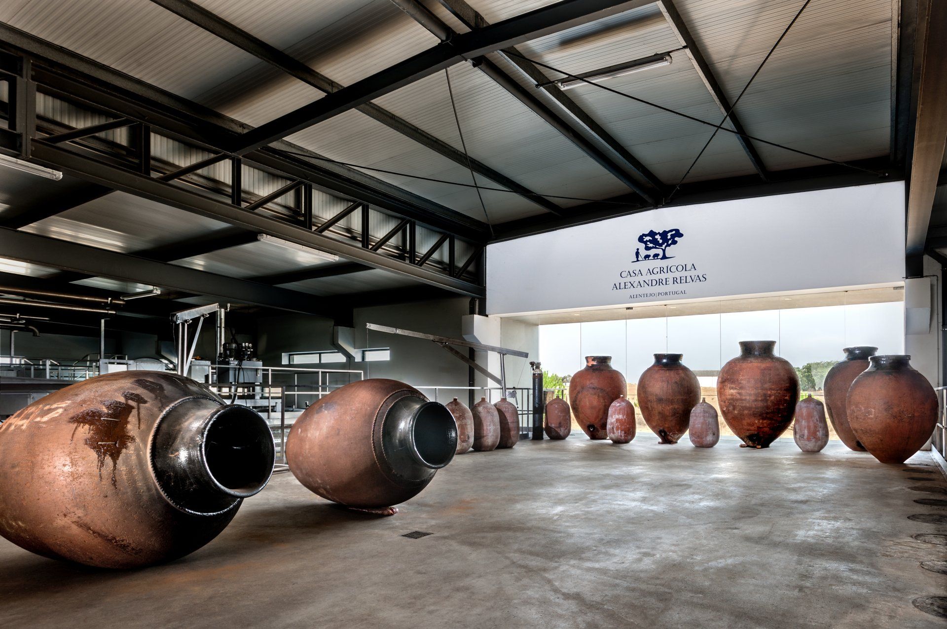 Large copper amphorae in a warehouse with a company sign visible.