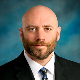 A bald man with a beard wearing a suit and tie