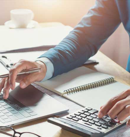 Man Using a Laptop and Calculator — Weston, WV — John E Law CPA, A.C. Man Using a Laptop and Calculator — Weston, WV — John E Law CPA, A.C.