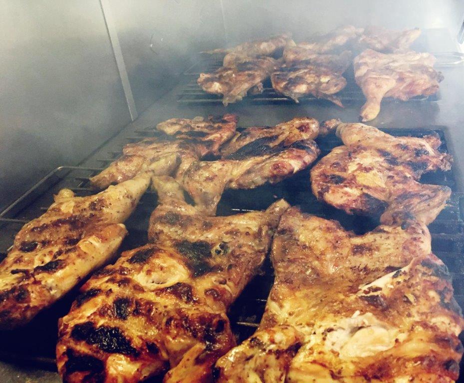 Mezzi polli grigliati su una griglia calda, fumanti, con i segni della griglia bruciacchiata.