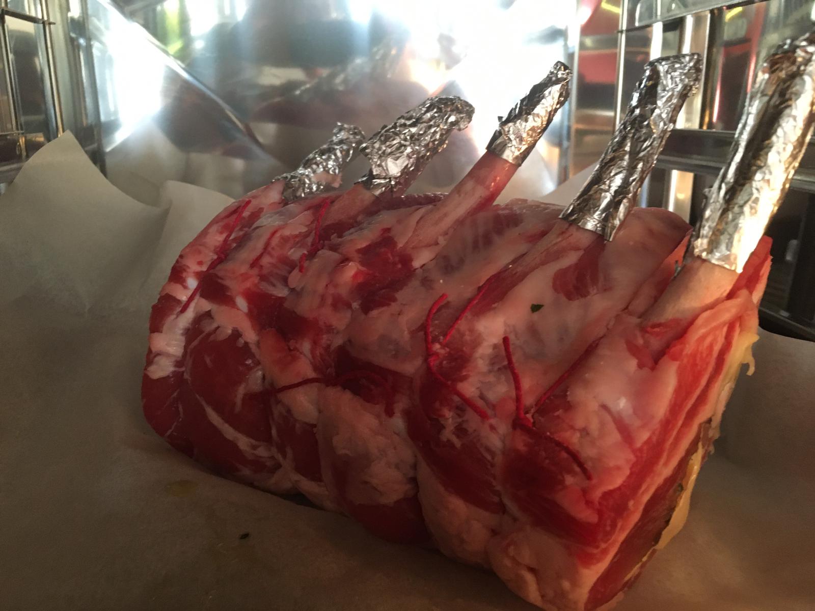 Arrosto di costata crudo con ossa avvolte in un foglio di alluminio su carta da forno, pronto per la cottura.