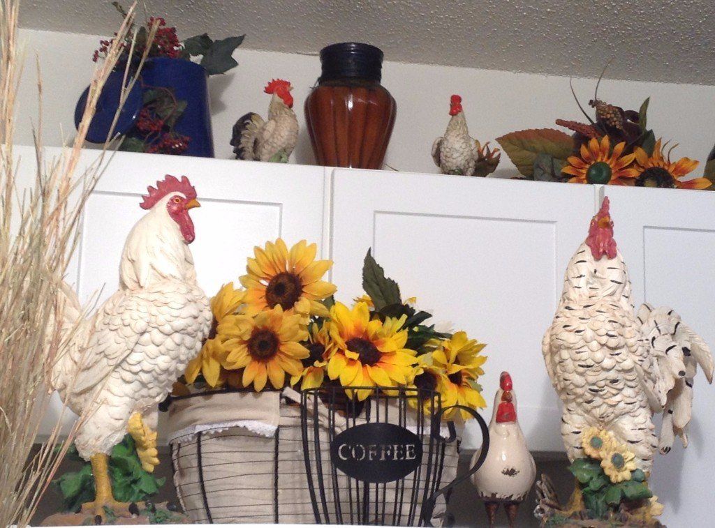 Roosters and sunflowers decorate a kitchen cabinet.