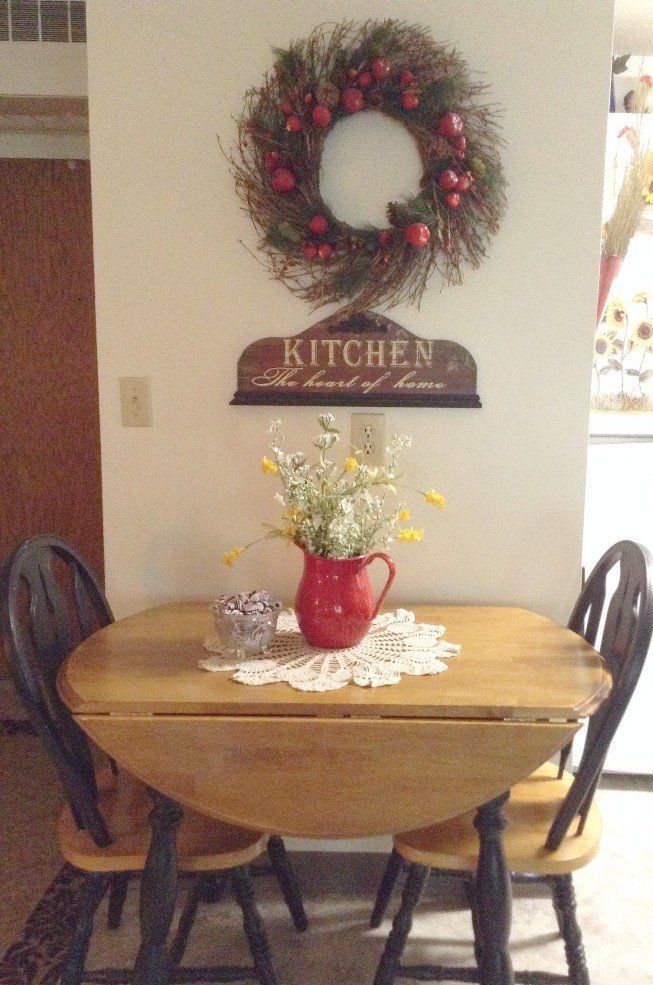 Wooden table and chairs below a wreath and