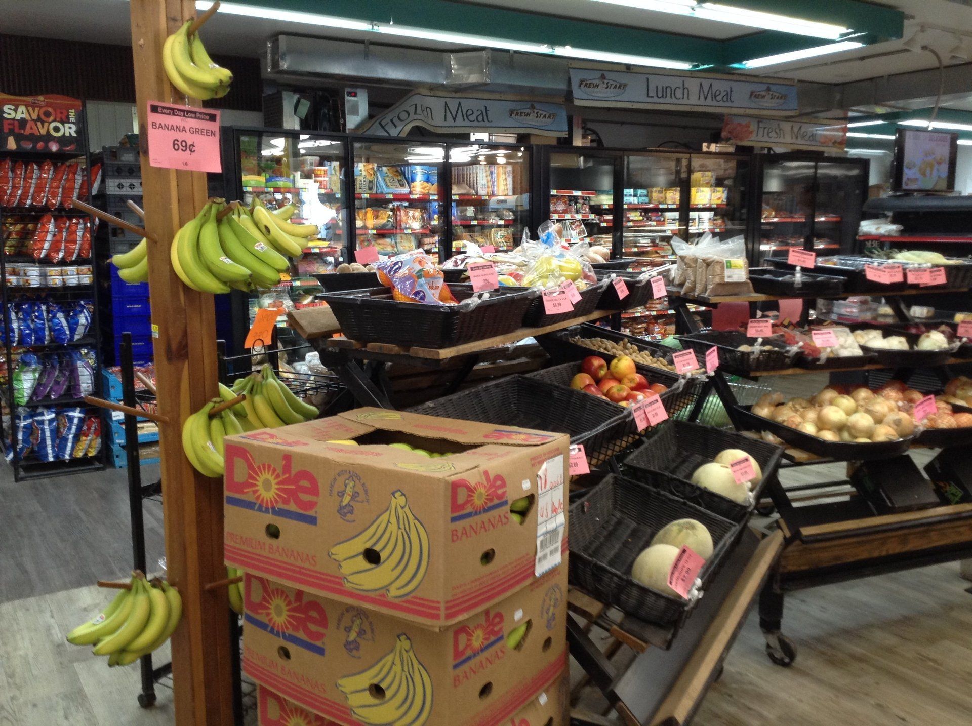 Grocery store interior with bananas on display and various products on shelves.