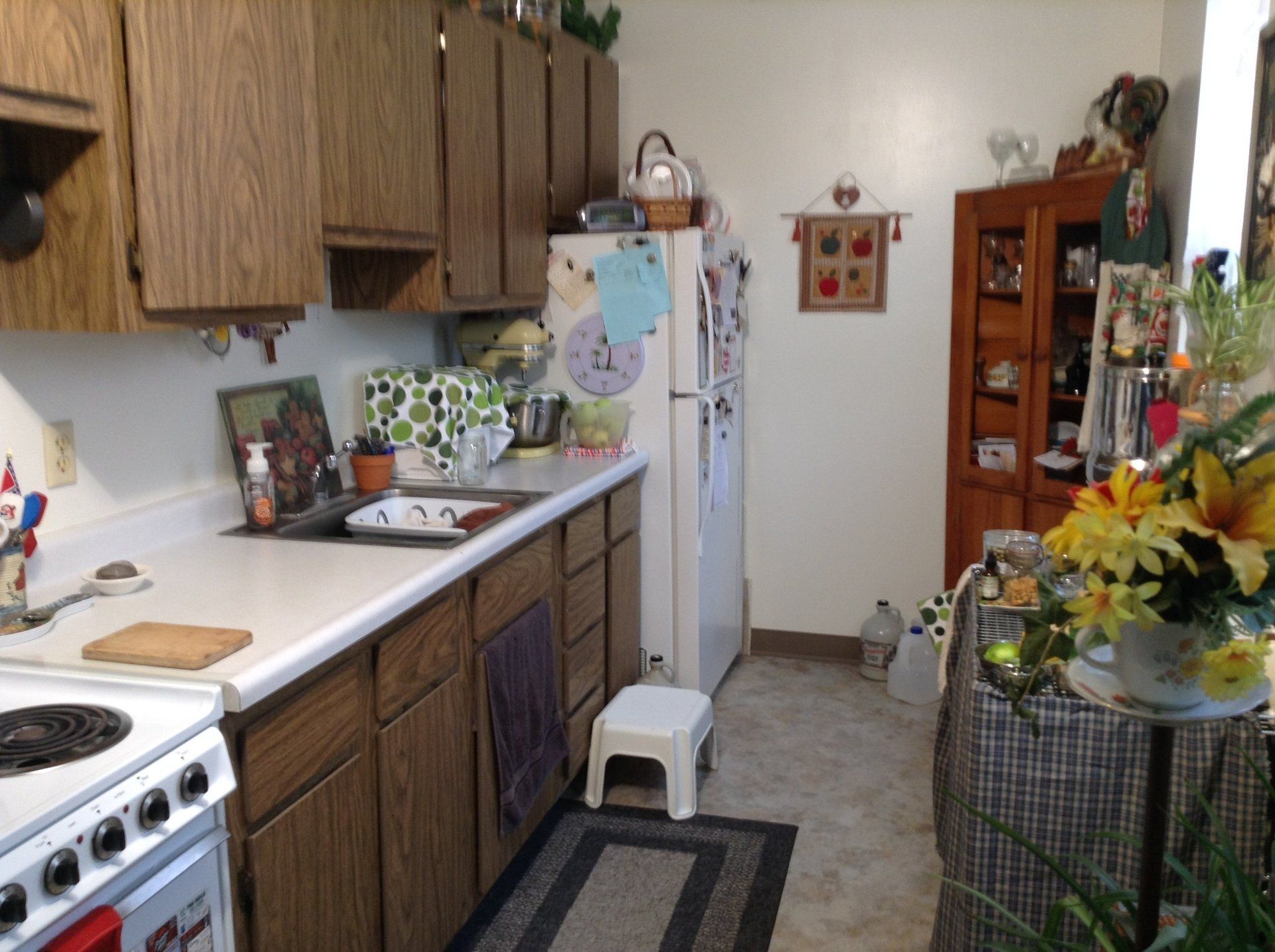 Kitchen with wooden cabinets, white appliances, and a small step stool.