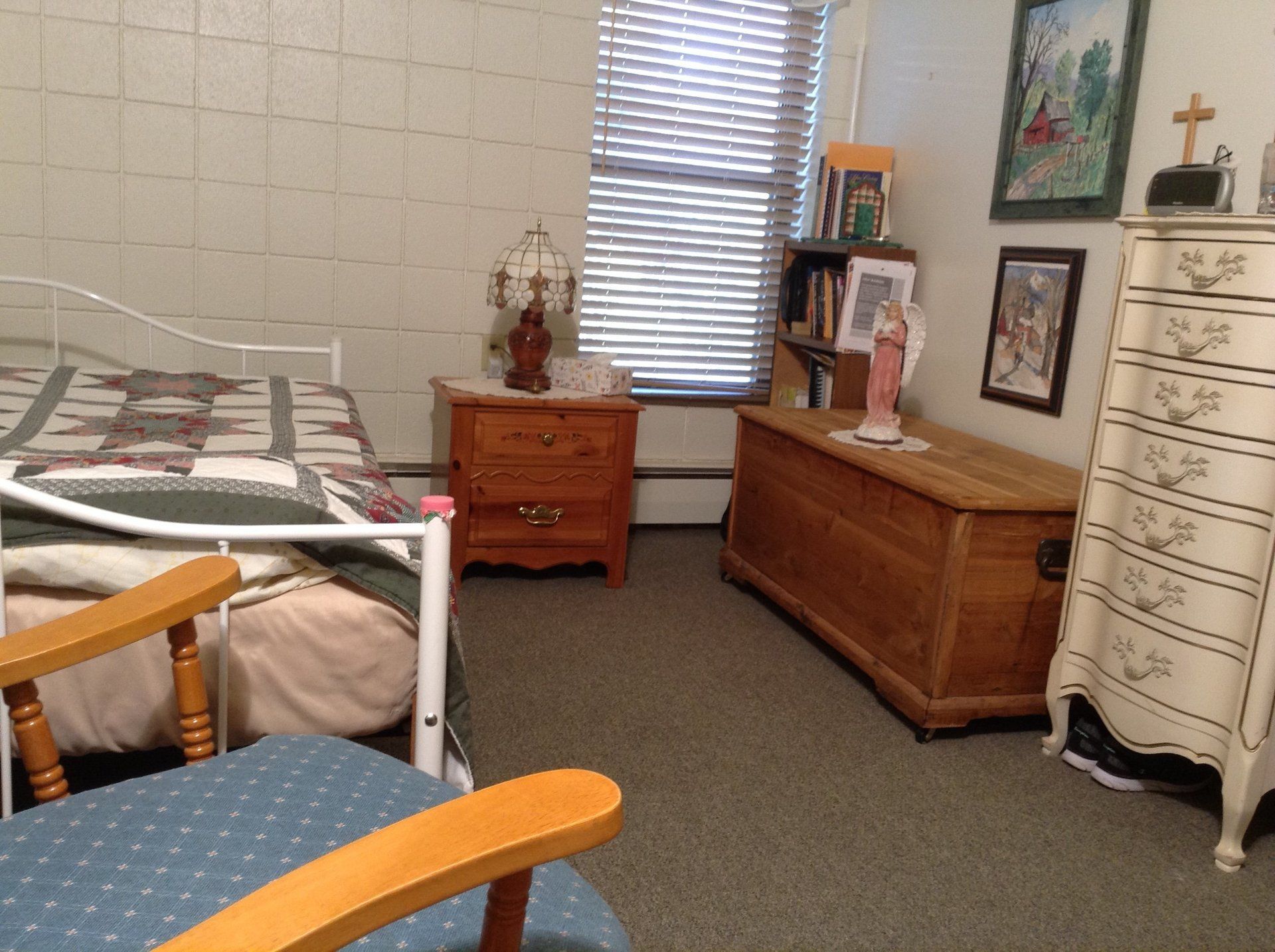 Bedroom with bed, furniture, window, and religious items.
