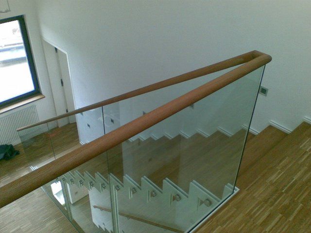 Eine Treppe mit einem Glasgeländer und einem Holzhandlauf