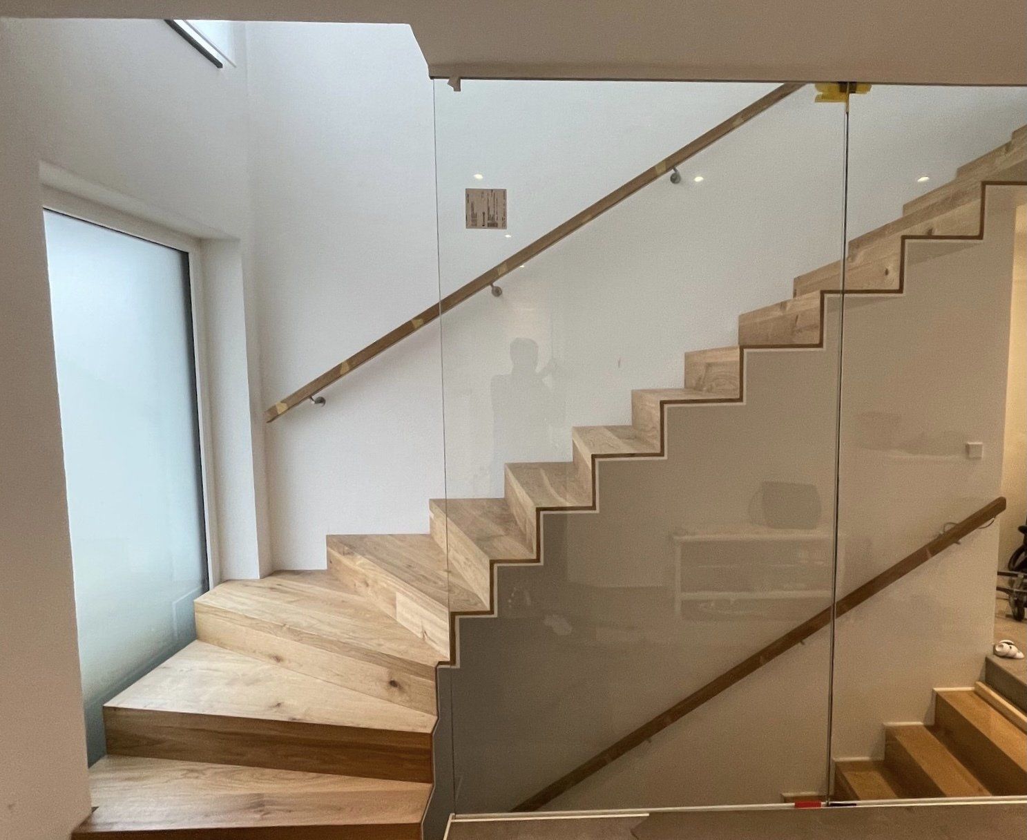 Eine Treppe mit einem Glasgeländer und einem Holzhandlauf