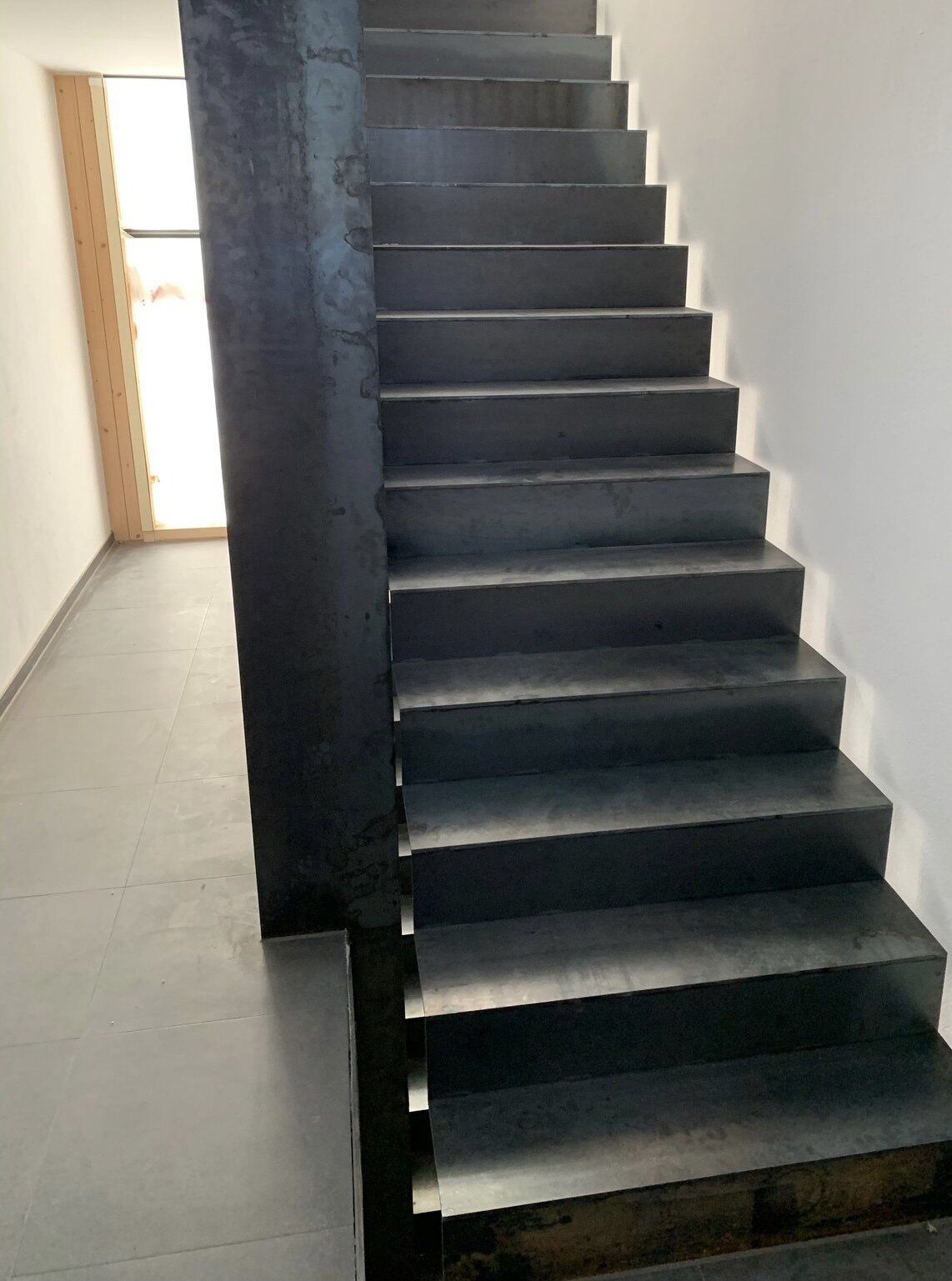 Eine schwarze Treppe führt in den zweiten Stock eines Gebäudes.