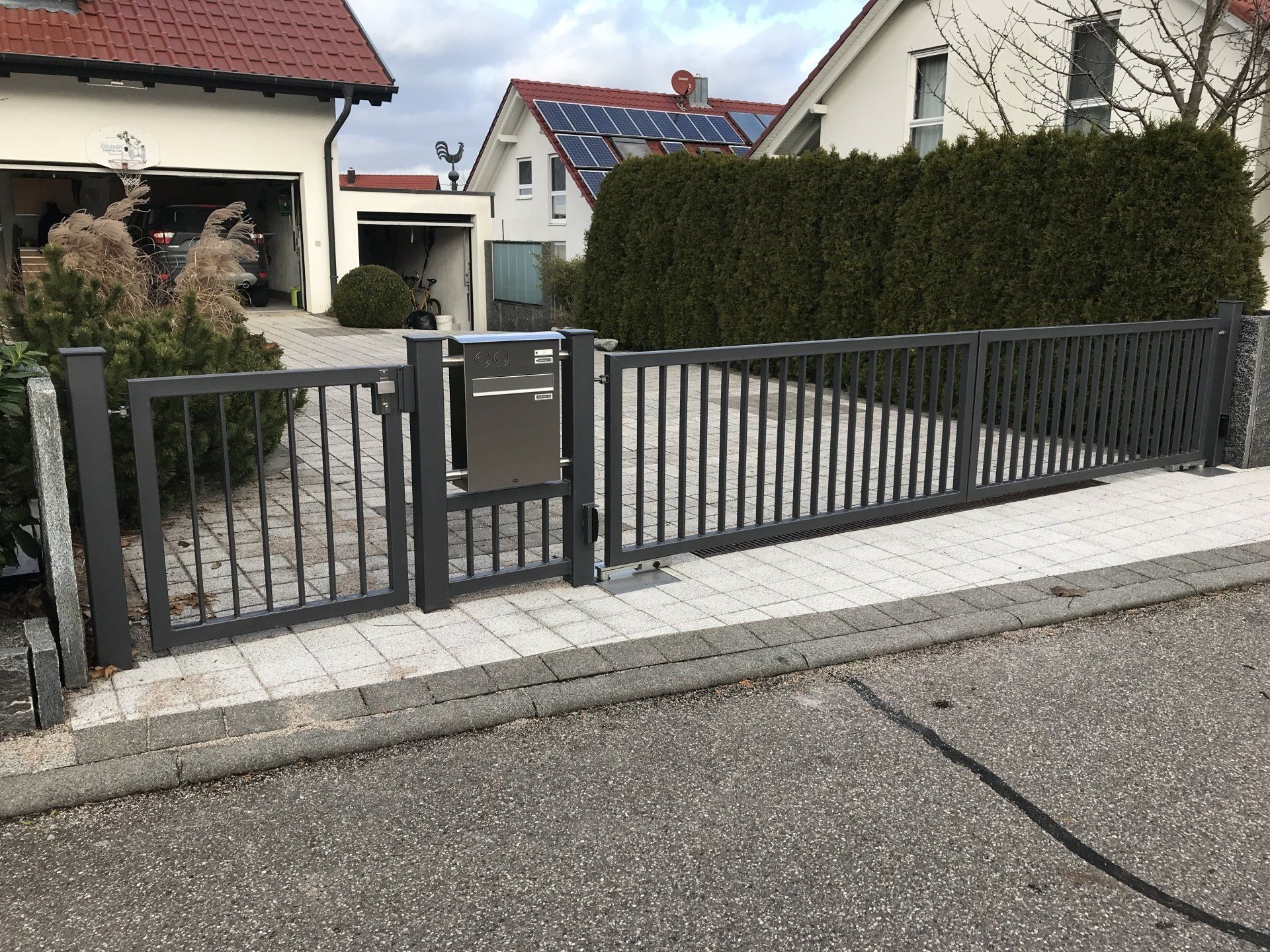 Ein Zaun mit einem Briefkasten vor einem Haus
