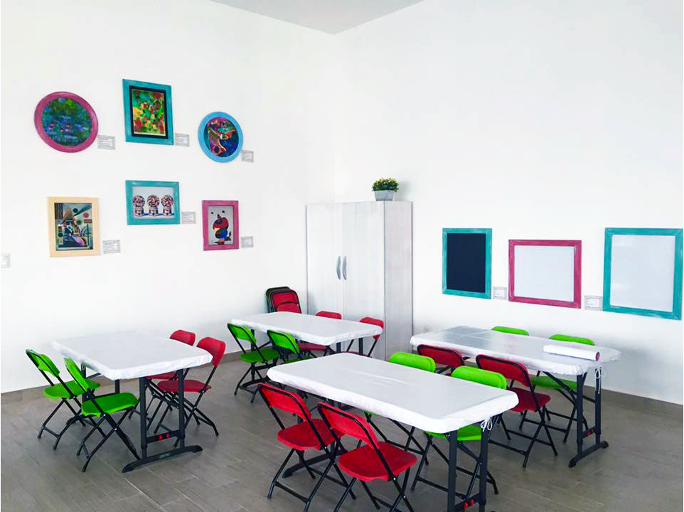 Un salón de clases con mesas y sillas y cuadros en las paredes.