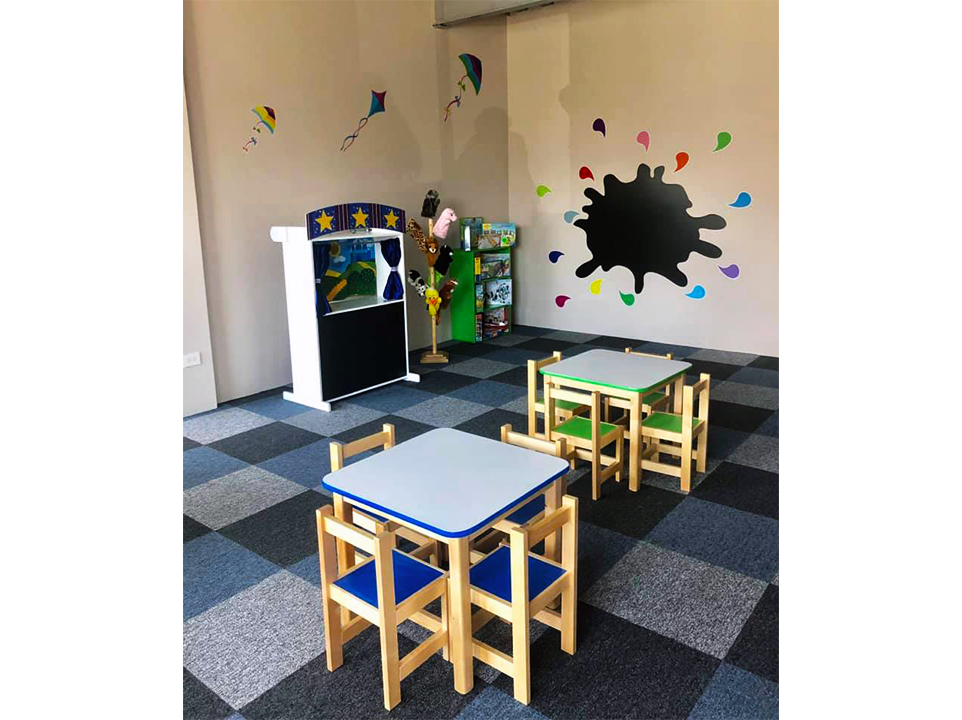 Una sala con mesas y sillas y una pizarra en la pared.