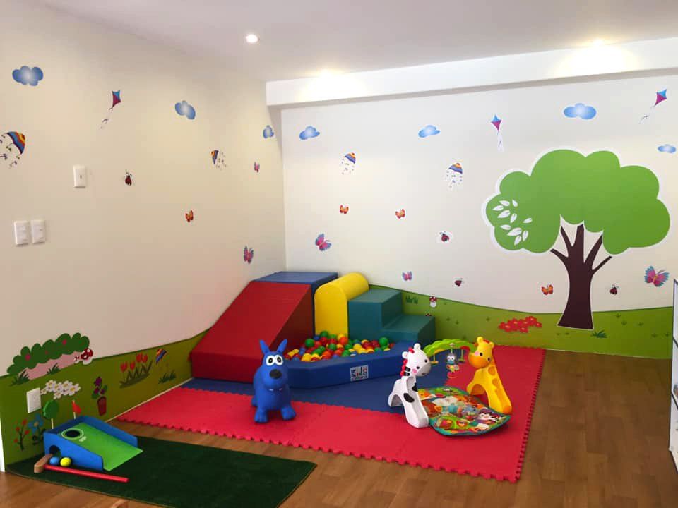 Una habitación con muchos juguetes y un árbol en la pared.
