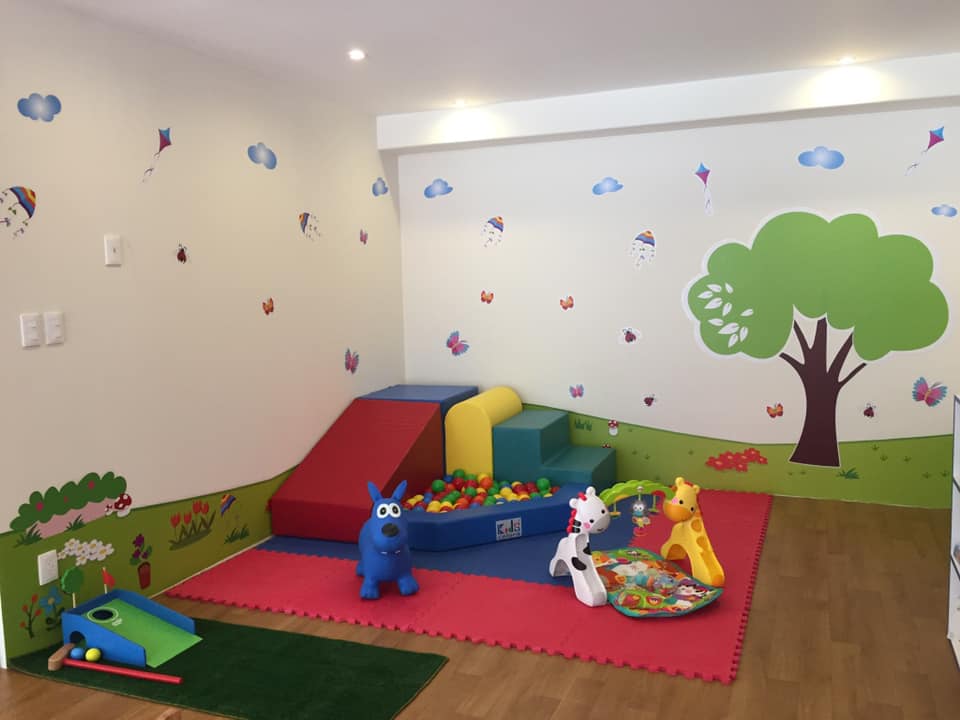 Una habitación con muchos juguetes y un árbol en la pared.