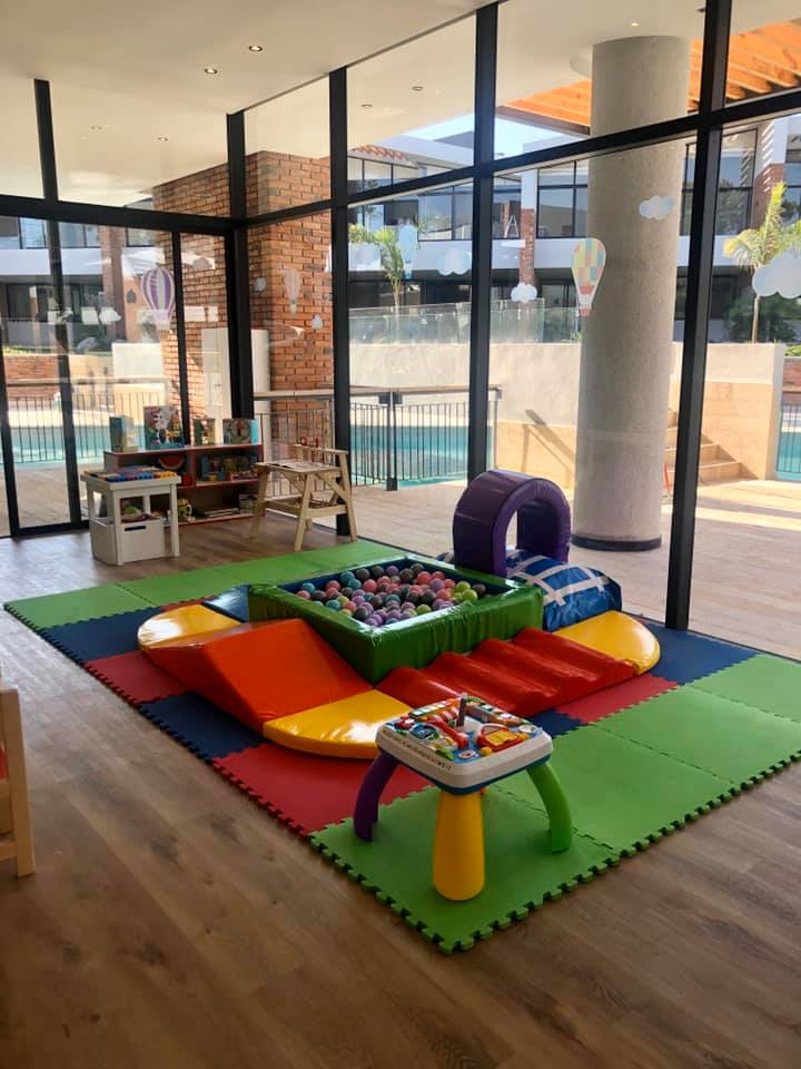 Un área de juegos infantiles con piscina de pelotas y mesa.